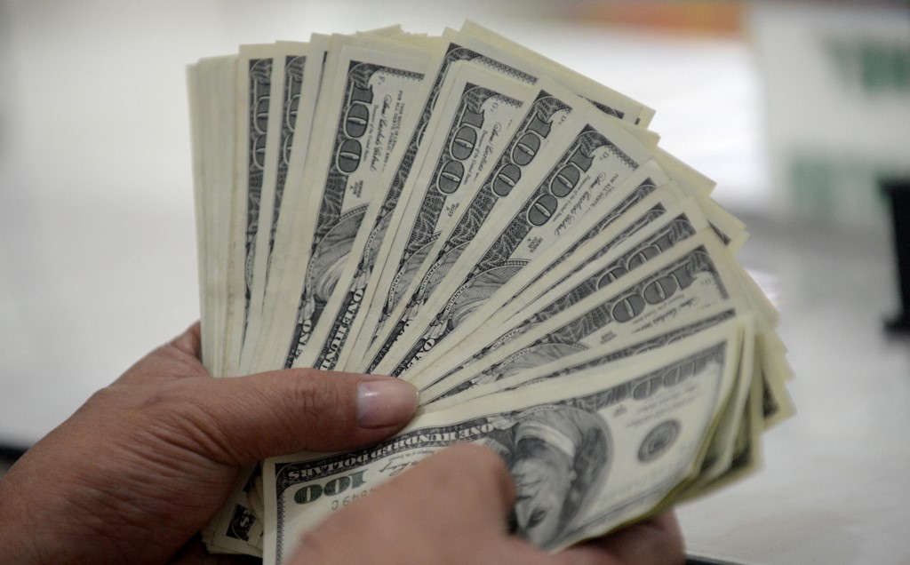 An employee at a money changer counts USD 100 bills as we look at our best betting sites for reduced juice
