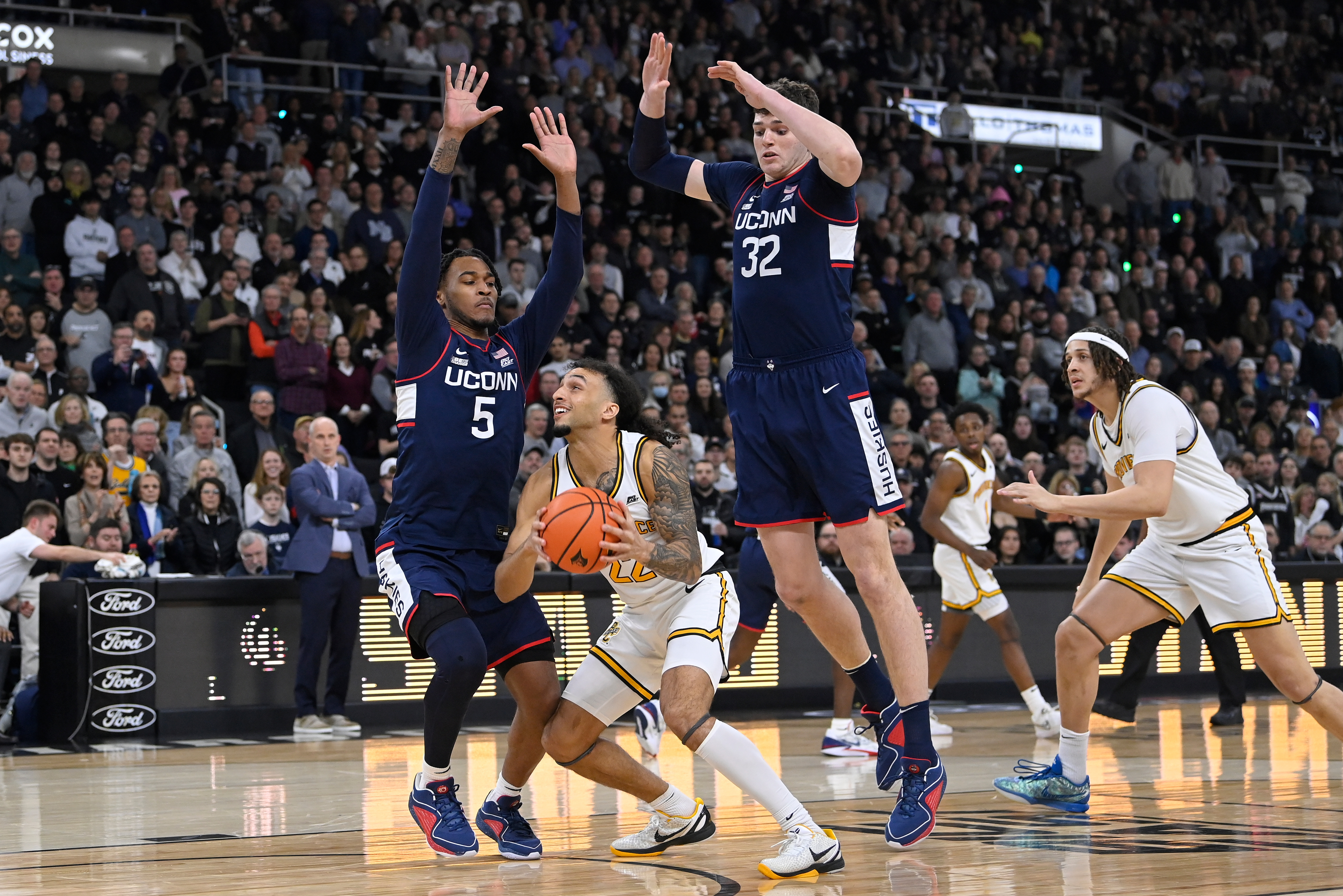 Providence Friars guard Devin Carter tries to shoot through the defense of UConn Huskies guard Stephon Castle and center Donovan Clingan. We focus on all three players in our 2025 NBA Rookie of the Year Predictions.