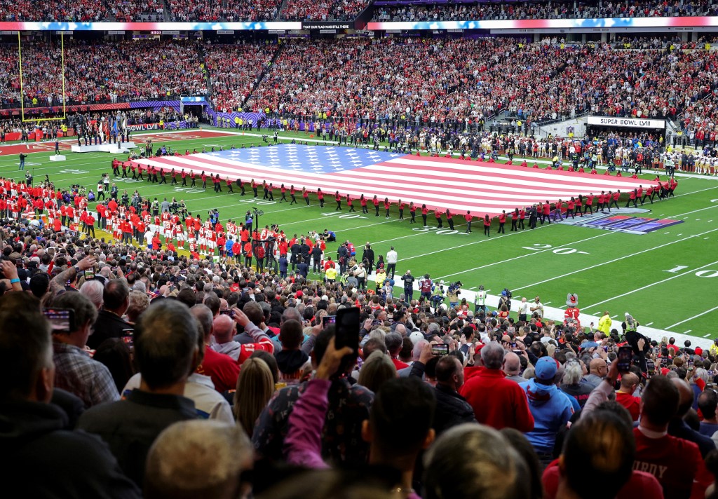 An American flag is displayed on the field as Reba McEntire sings the United States national anthem before Super Bowl LVIII in Las Vegas.