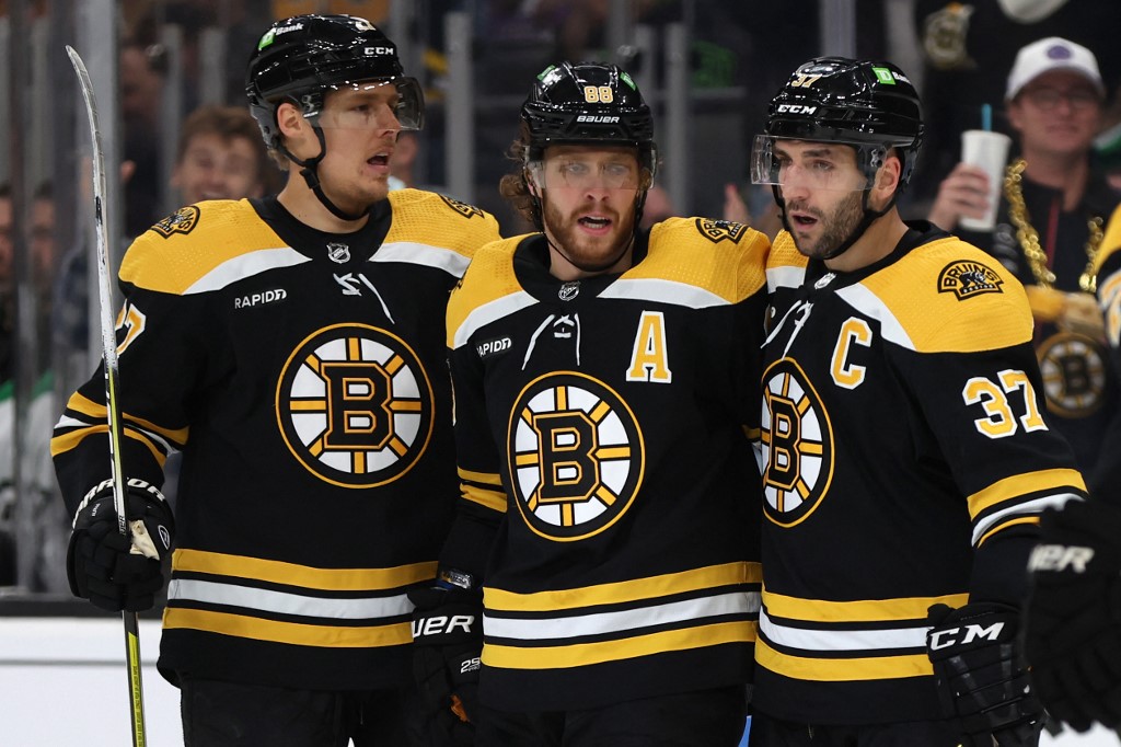 David Pastrnak of the Boston Bruins celebrates with Hampus Lindholm and Patrice Bergeron after scoring a goal against the Dallas Stars during the first period at TD Garden.