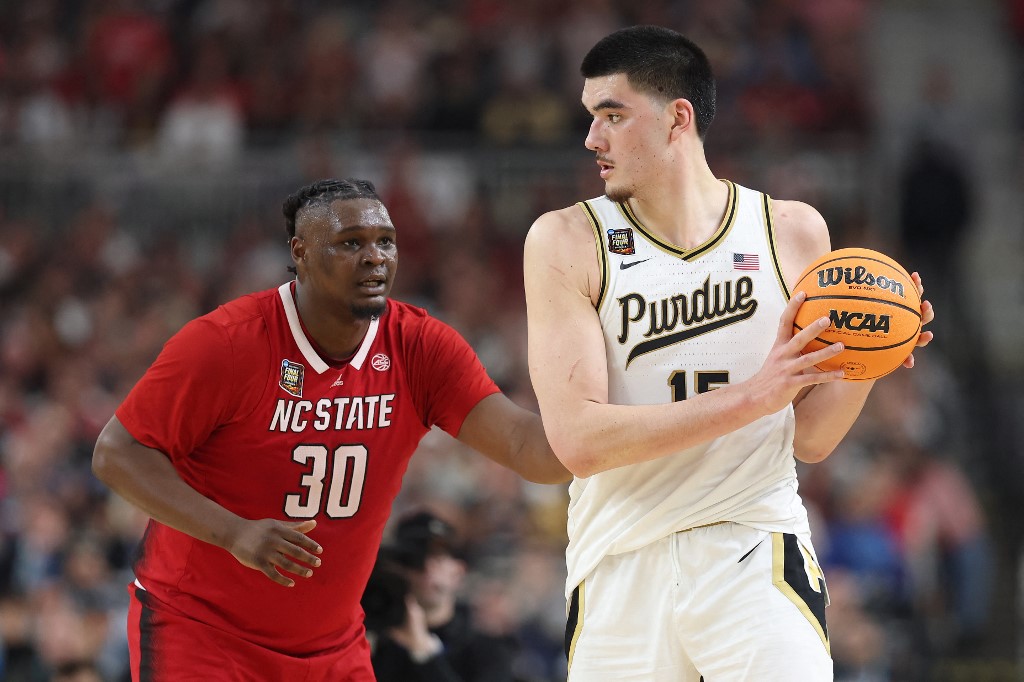 Zach Edey of the Purdue Boilermakers handles the ball while being guarded by D.J. Burns Jr. of the NC State Wolfpack in the NCAA Men's Basketball Tournament Final Four semifinal game. We're looking at our Purdue vs. UConn Zach Edey play props.