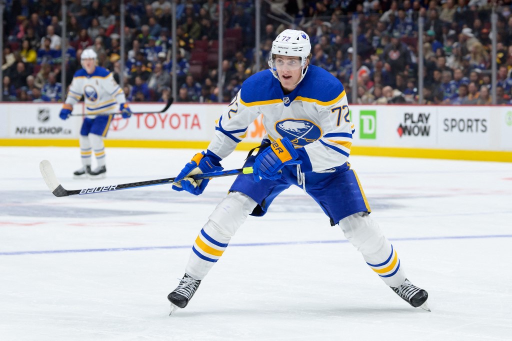 Buffalo Sabres center Tage Thompson skates up the ice with his stick raised, ready to shoot.