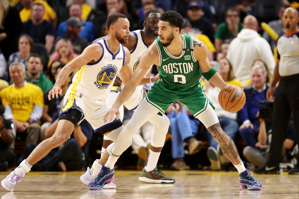 Jayson Tatum of the Boston Celtics dribbles against Stephen Curry of the Golden State Warriors.