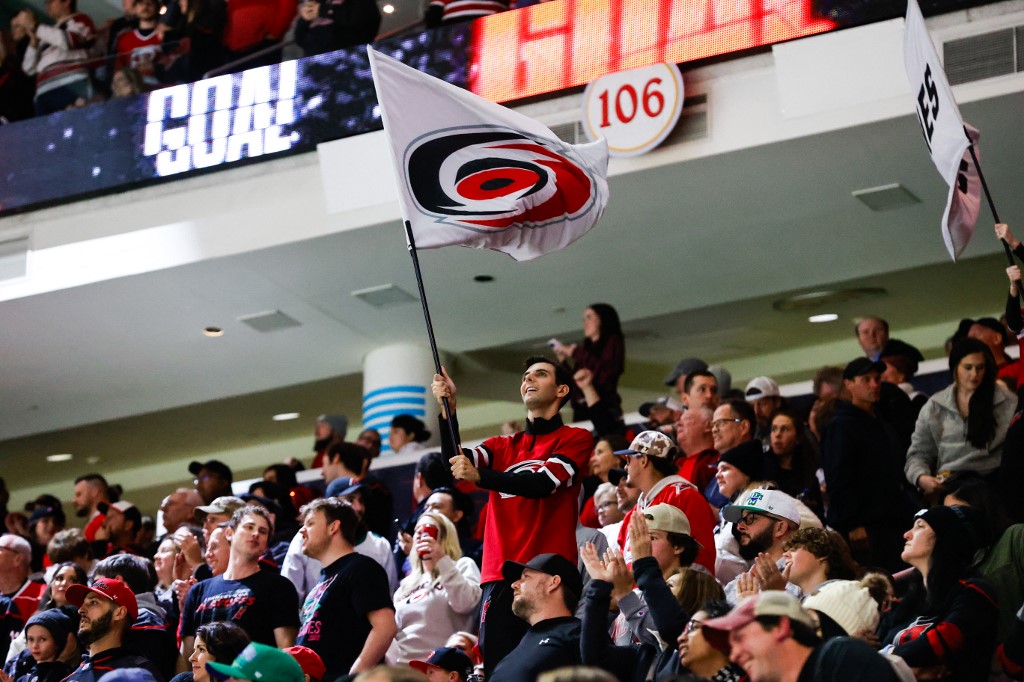 Carolina Hurricanes Storm Crew waves a flag during the third period of a game, and the team has officially partnered with Fanatics Underscoreg.