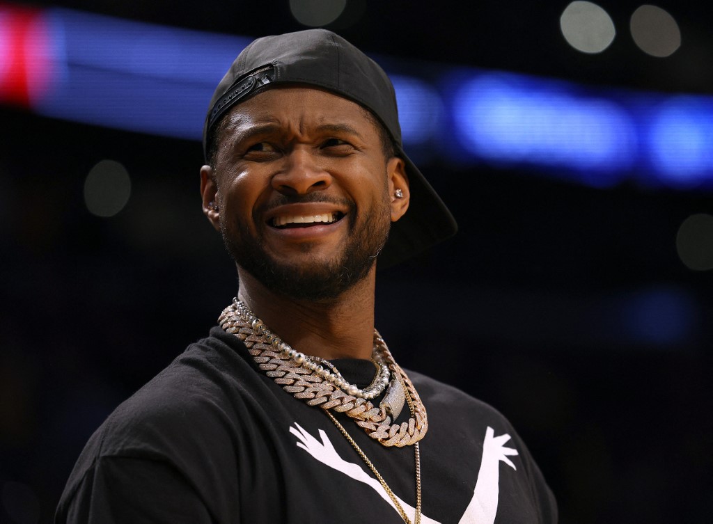 Usher reacts from the sidelines during an NBA game between the Los Angeles Lakers and Oklahoma City Thunder, and we offer our top predictions for the Super Bowl halftime show first song based on the best NFL odds.