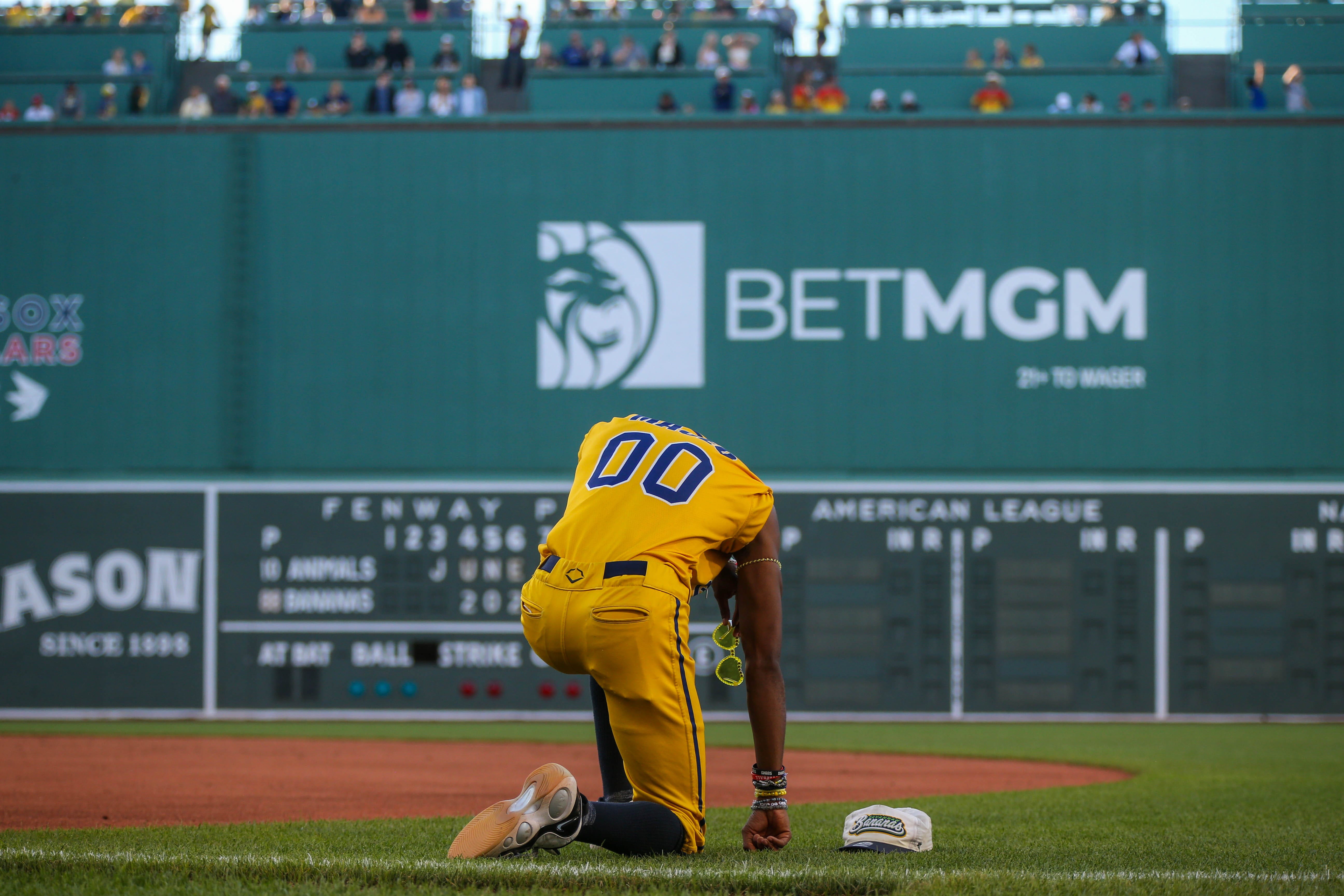 Dancing first base coach Maceo Harrison kneels on the field as we look at the partnership between BetMGM and GameCode to expand BetMGM's slot offerings.