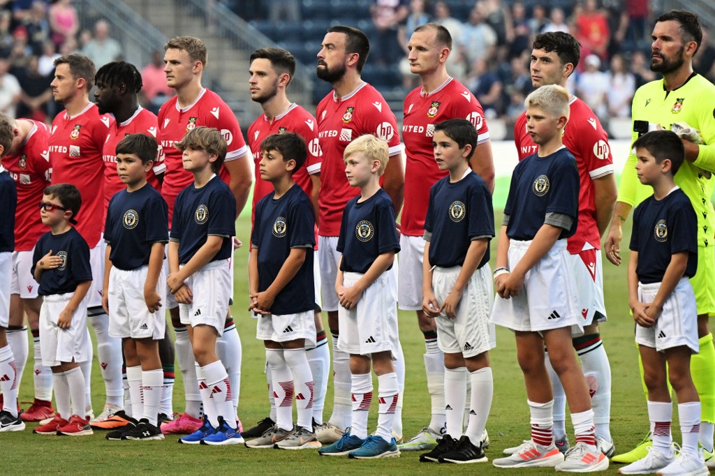 Wrexham AFC players stand for the national anthem before a pre-season friendly, and we offer new U.S. bettors our exclusive BetRivers promo code for Wrexham vs. Wigan.