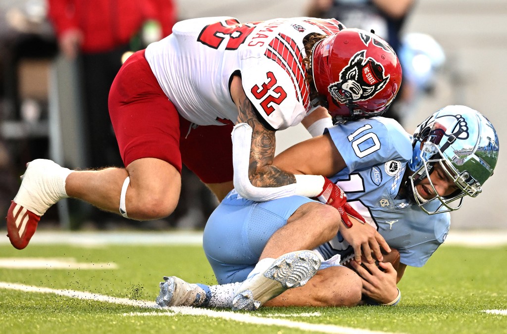 Drake Thomas of the NC State Wolfpack sacks Drake Maye of the North Carolina Tar Heels during the first half of their game at Kenan Memorial Stadium.