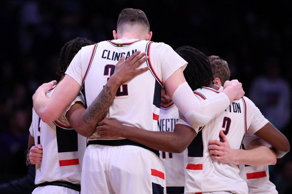 UConn Huskies players huddle as we look at our Purdue vs. UConn Parlay prediction.
