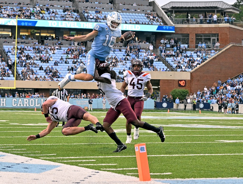 Drake Maye of the North Carolina Tar Heels hurdles Nasir Peoples of the Virginia Tech Hokies during the second half of their game at Kenan Memorial Stadium on October 01, 2022 in Chapel Hill, North Carolina.