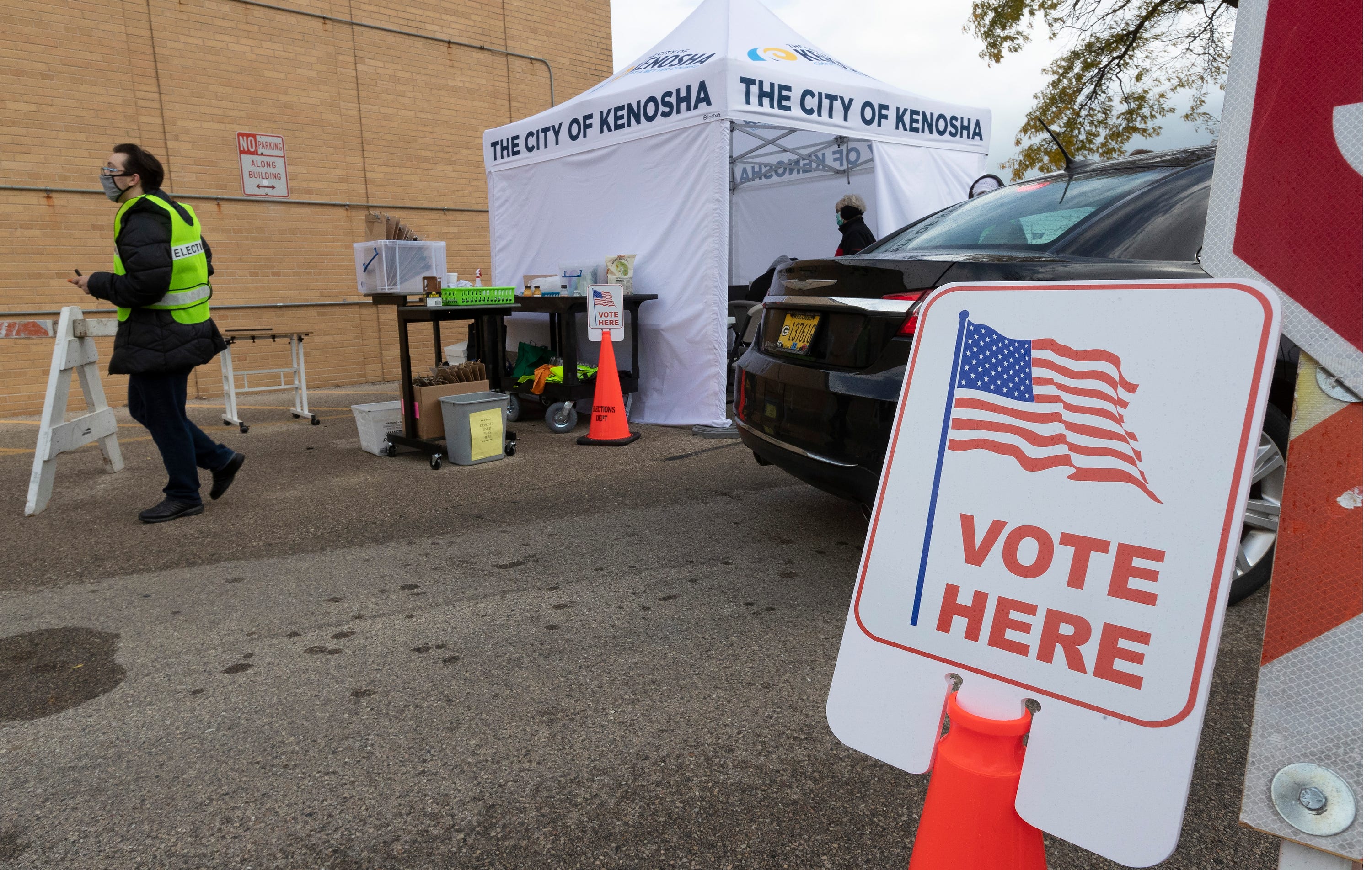 Election workers assist drive-up voters Thursday, October 29, 2020 at the Kenosha Municipal Building in Kenosha, Wis.